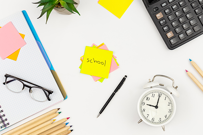 Notebooks, glasses, calculator and paper reminders on a white background, top view, copy space.